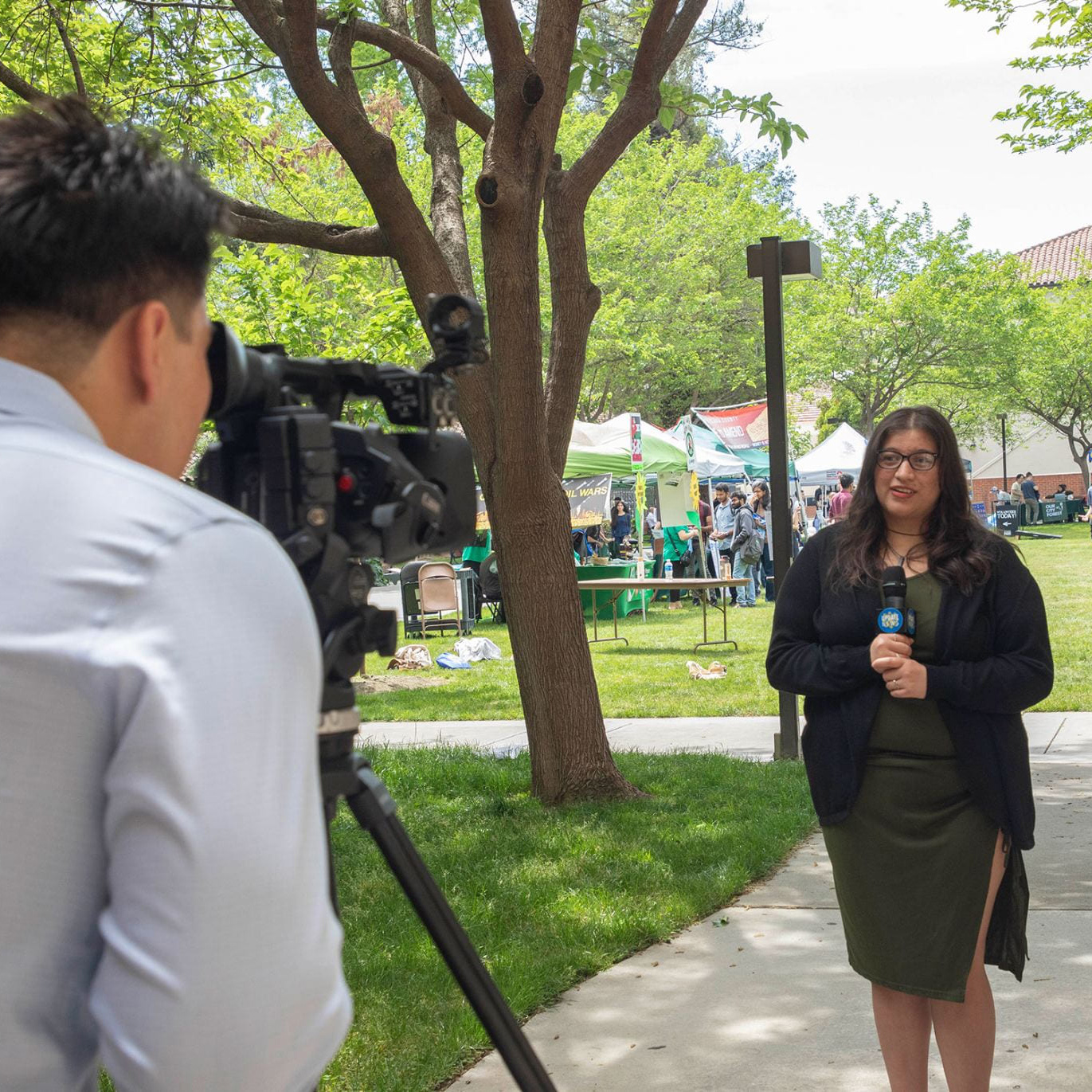 Female news reporter in front of a camera at tower lawn at SJSU.