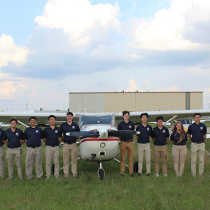17 members of the SJSU Precision Flight Team in front of an aircraft at the at the National Intercollegiate Flying Association (NIFA) Competition in Janesville, Wisconsin.