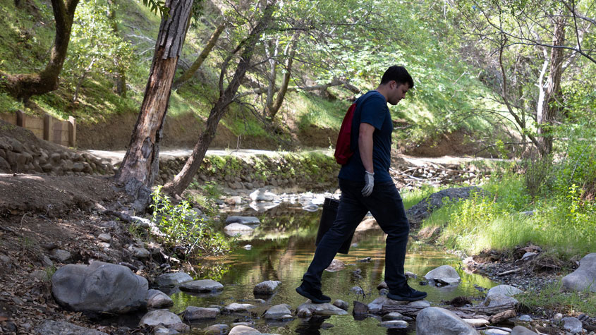 Edgar McGregor, ’23 Climate Science, walking across a creek.
