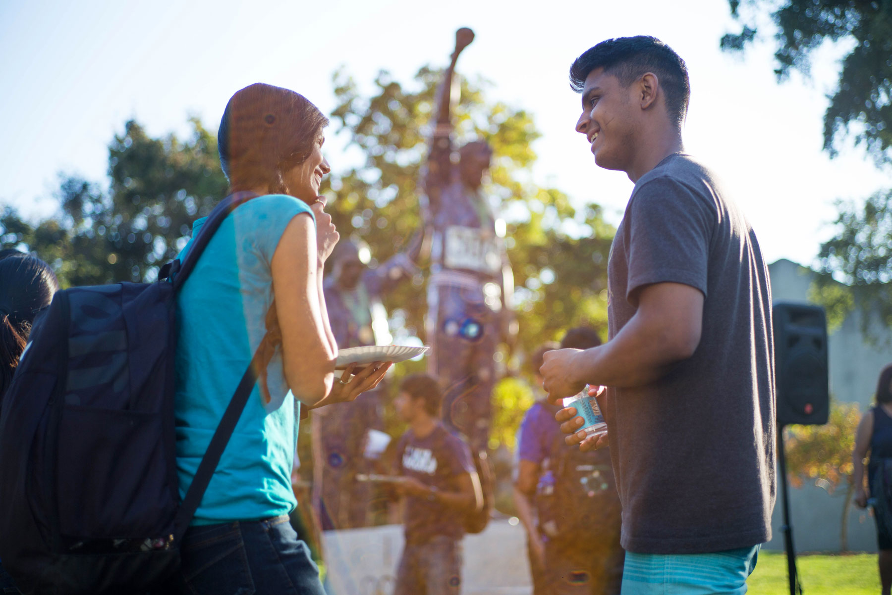 two students speaking in front of statue