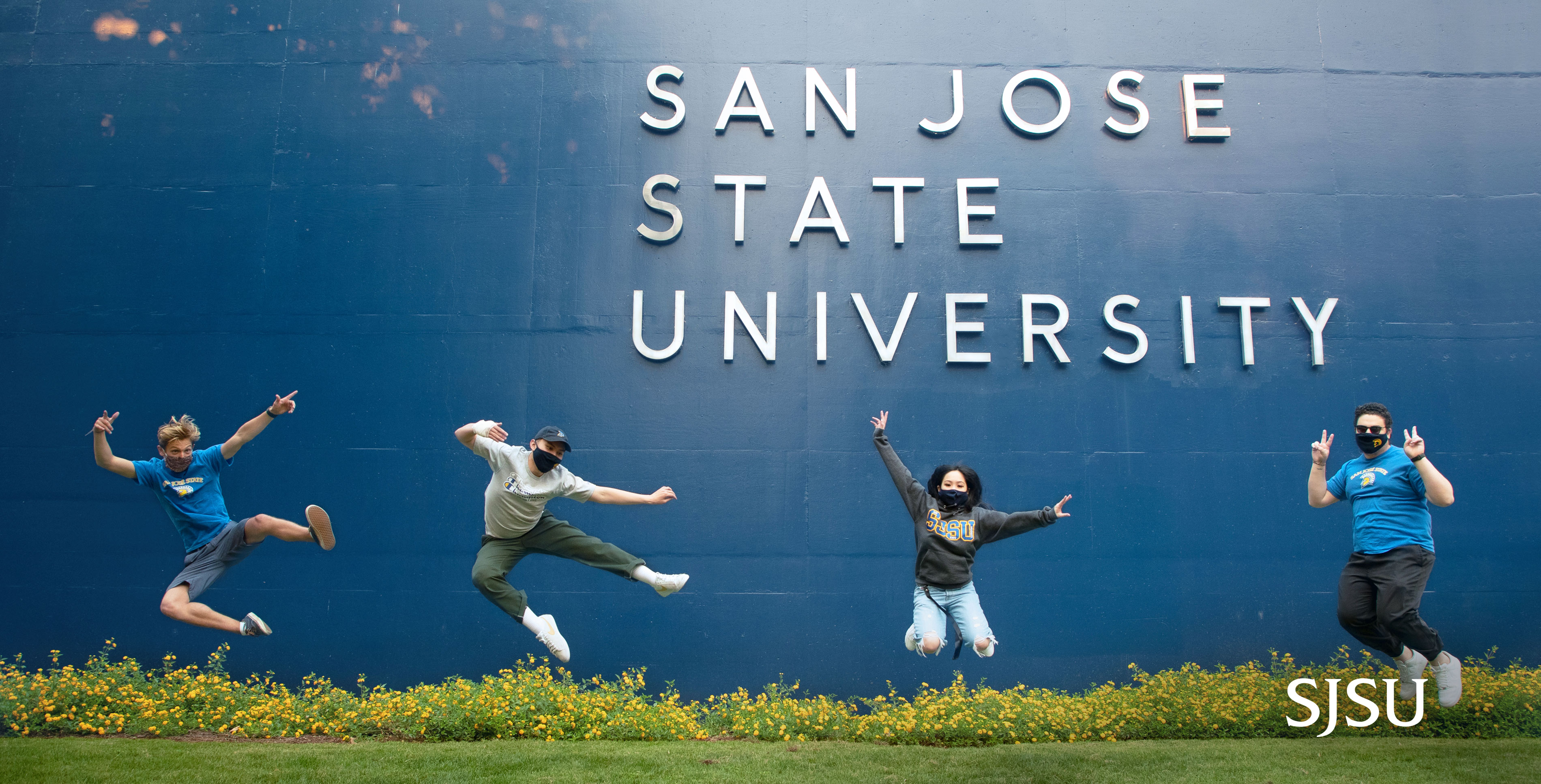 Students jumping with SJSU name in background on building
