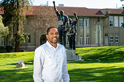 Black male in white dress shirt in front of Victory statue at SJSU