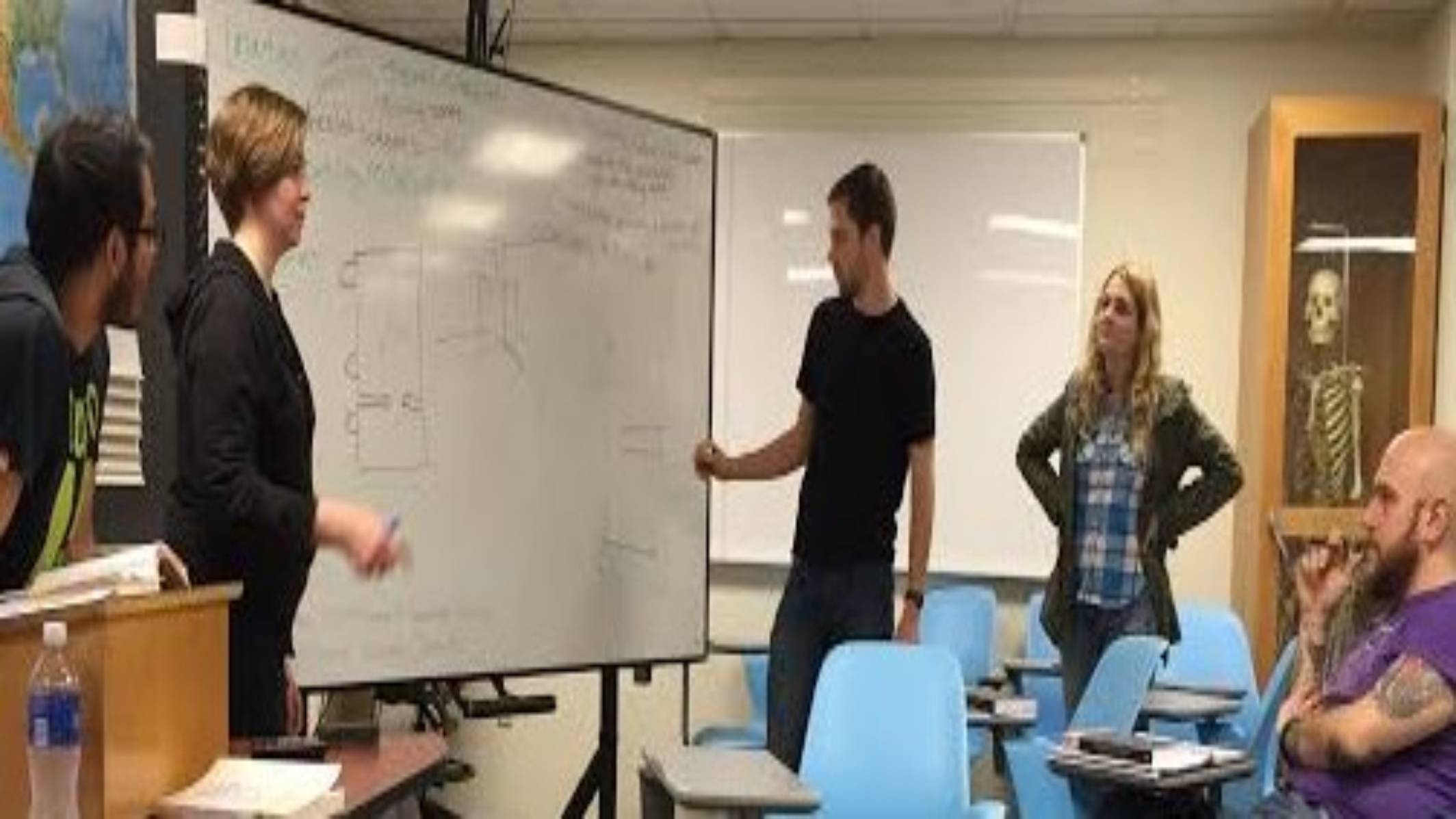 Students presenting in front of a white board.