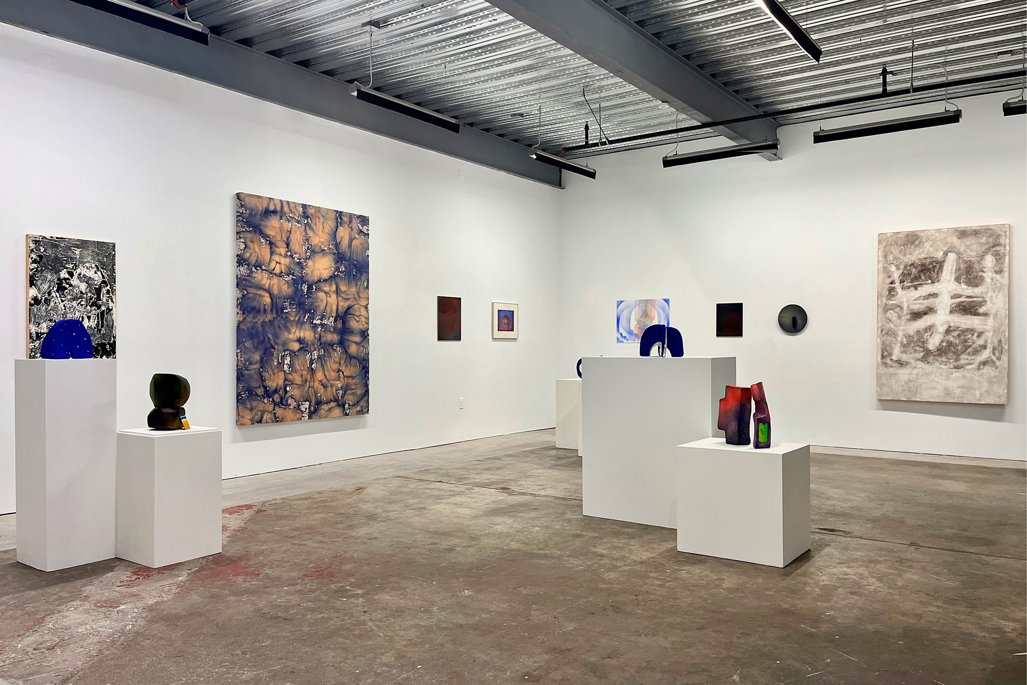 Installation view featuring abstract paintings and sculptures