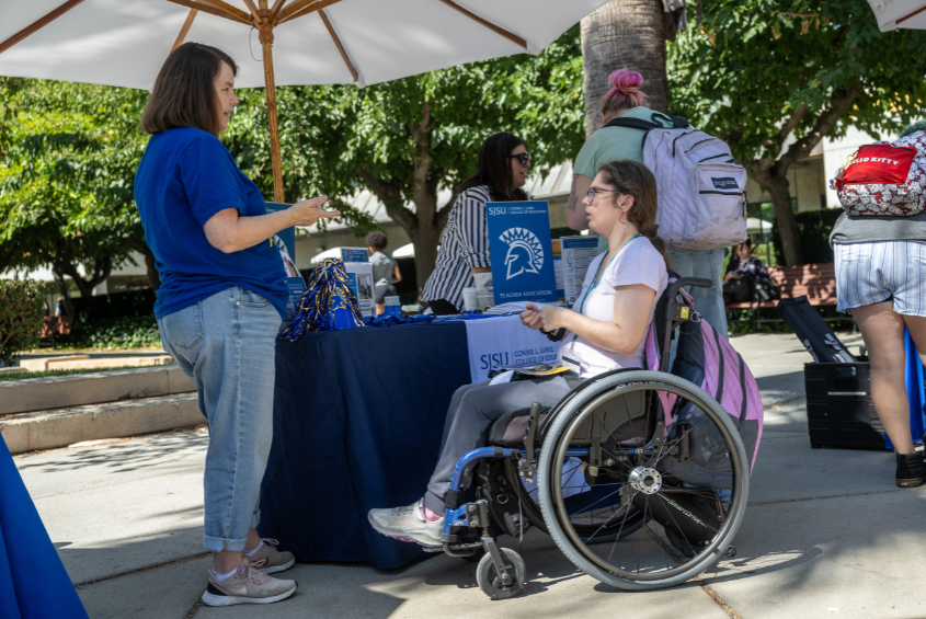 Student in a wheelchair talking to a staff member.
