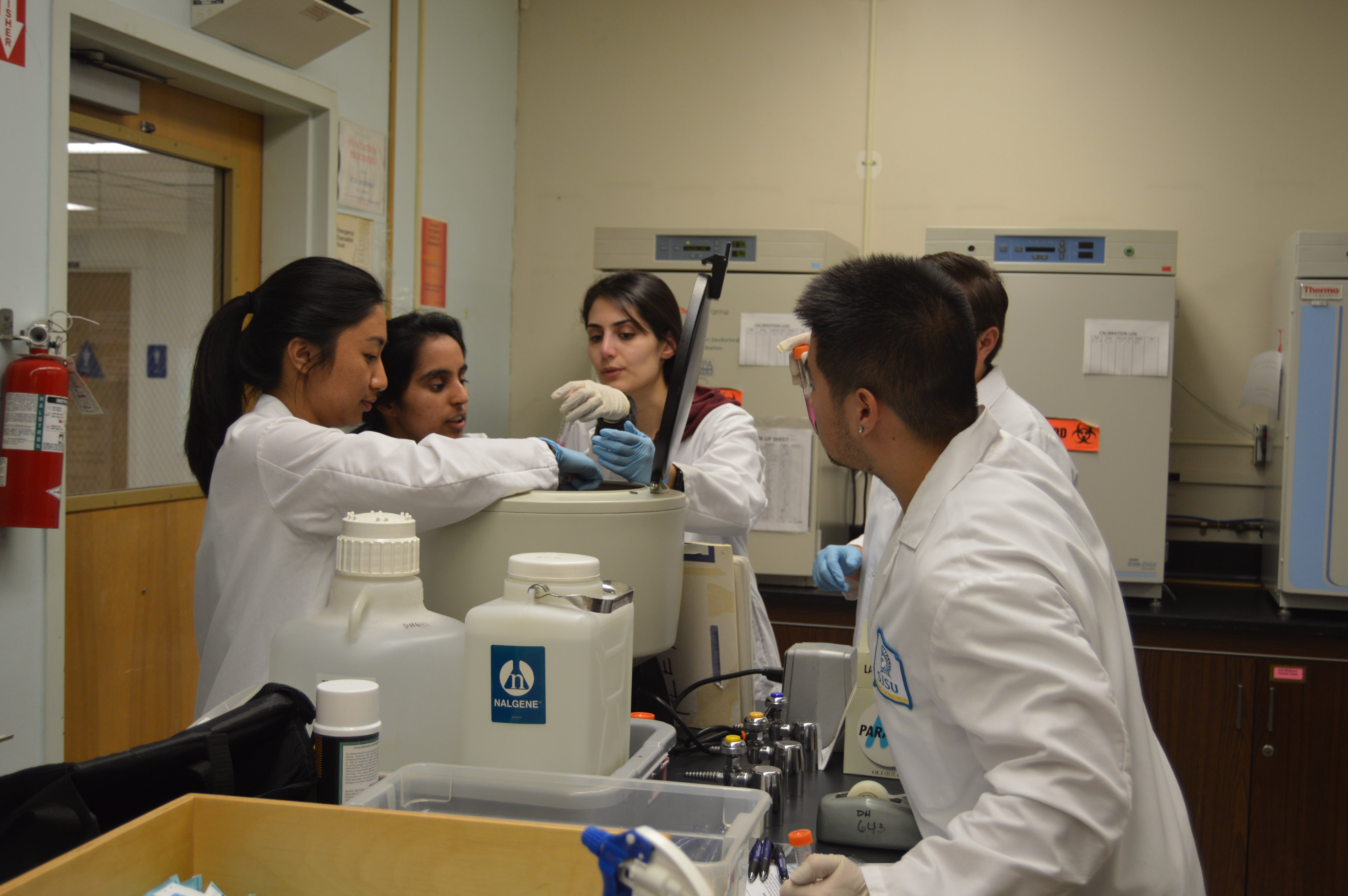 A group of students, some wearing lab coats