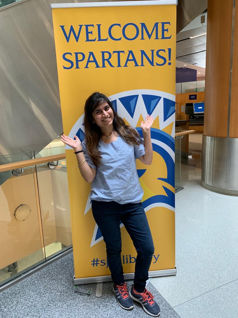 Divya Puraswani poses in front of a Spartan-themed banner.