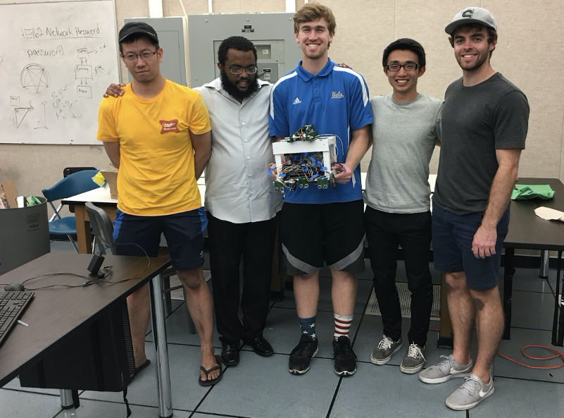 Samuel Semahegn stands with his UCLA team while holding a robot prototype.