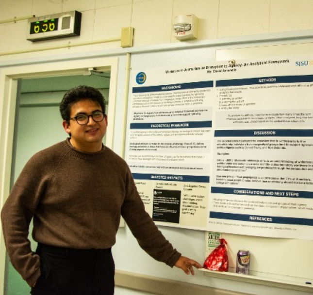 David Amancio smiling in front of a poster
