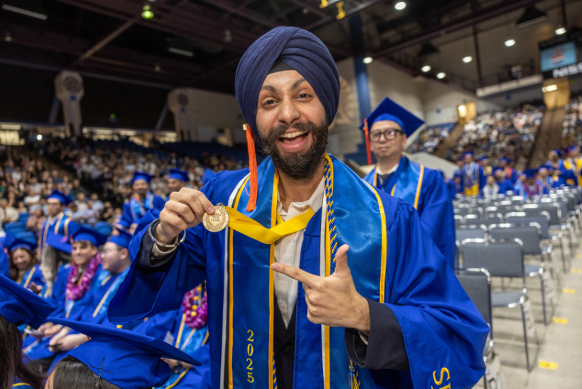 Graduate holding up their honors medallion