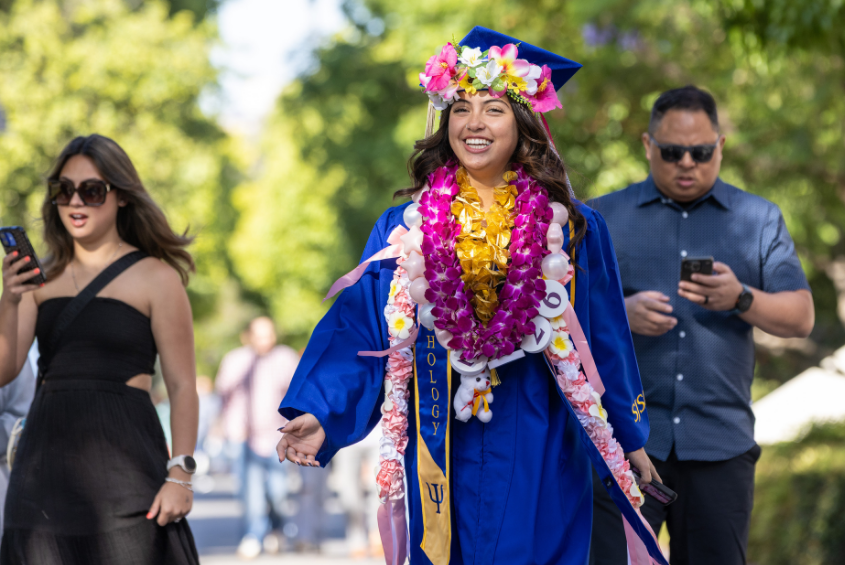Student adorned with flower leis walking.