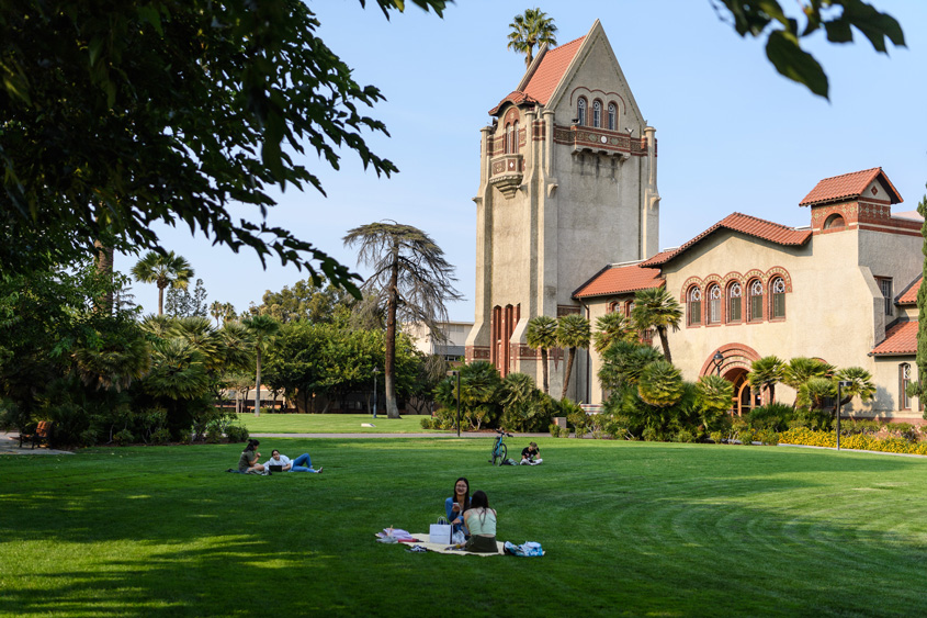 Students relaxing on the lawn by Tower Hall on campus.