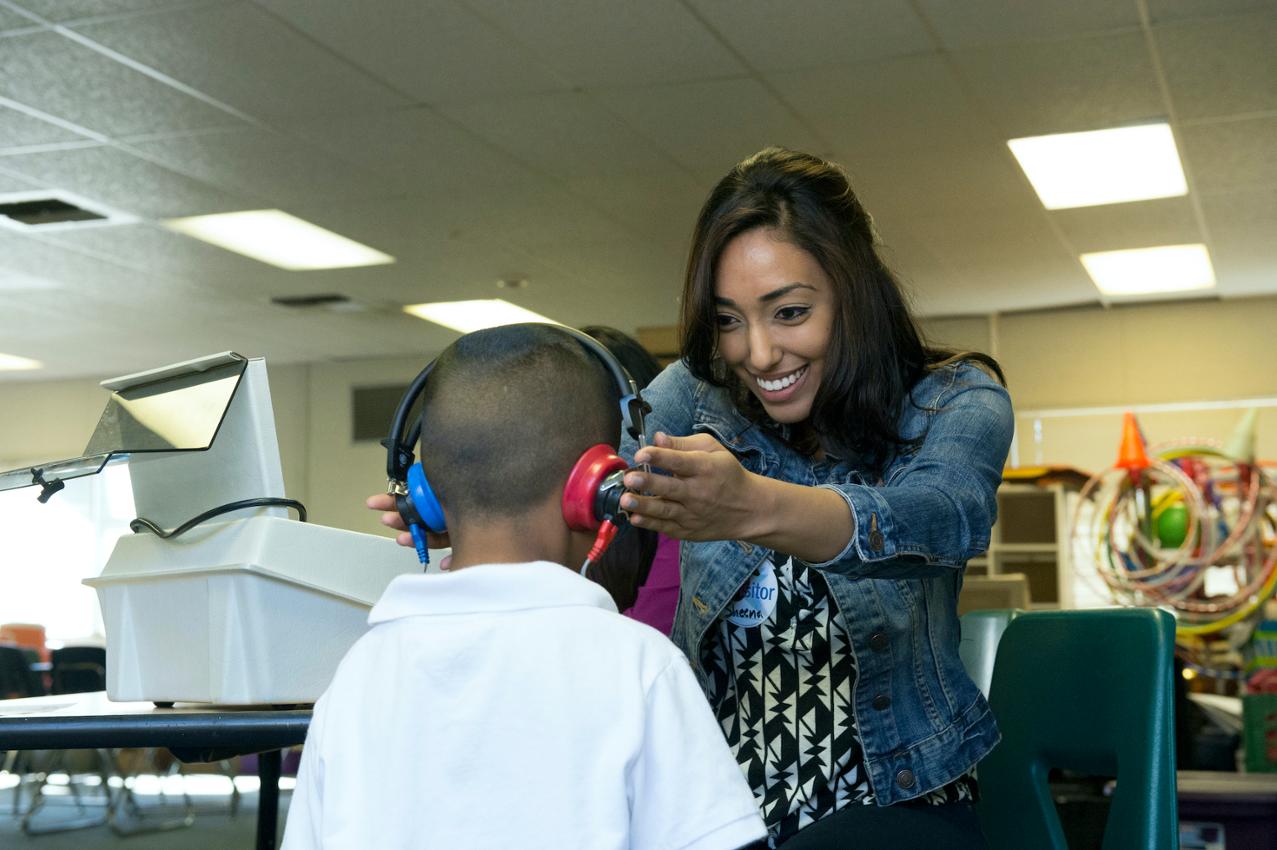 Audiology student assists client with headphones