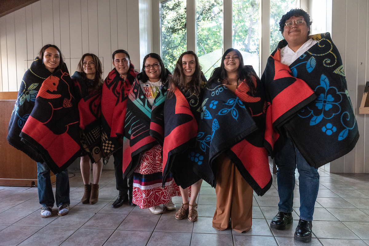 Native Grad students wrapped in blankets gifted by the SJSU Indigenous community