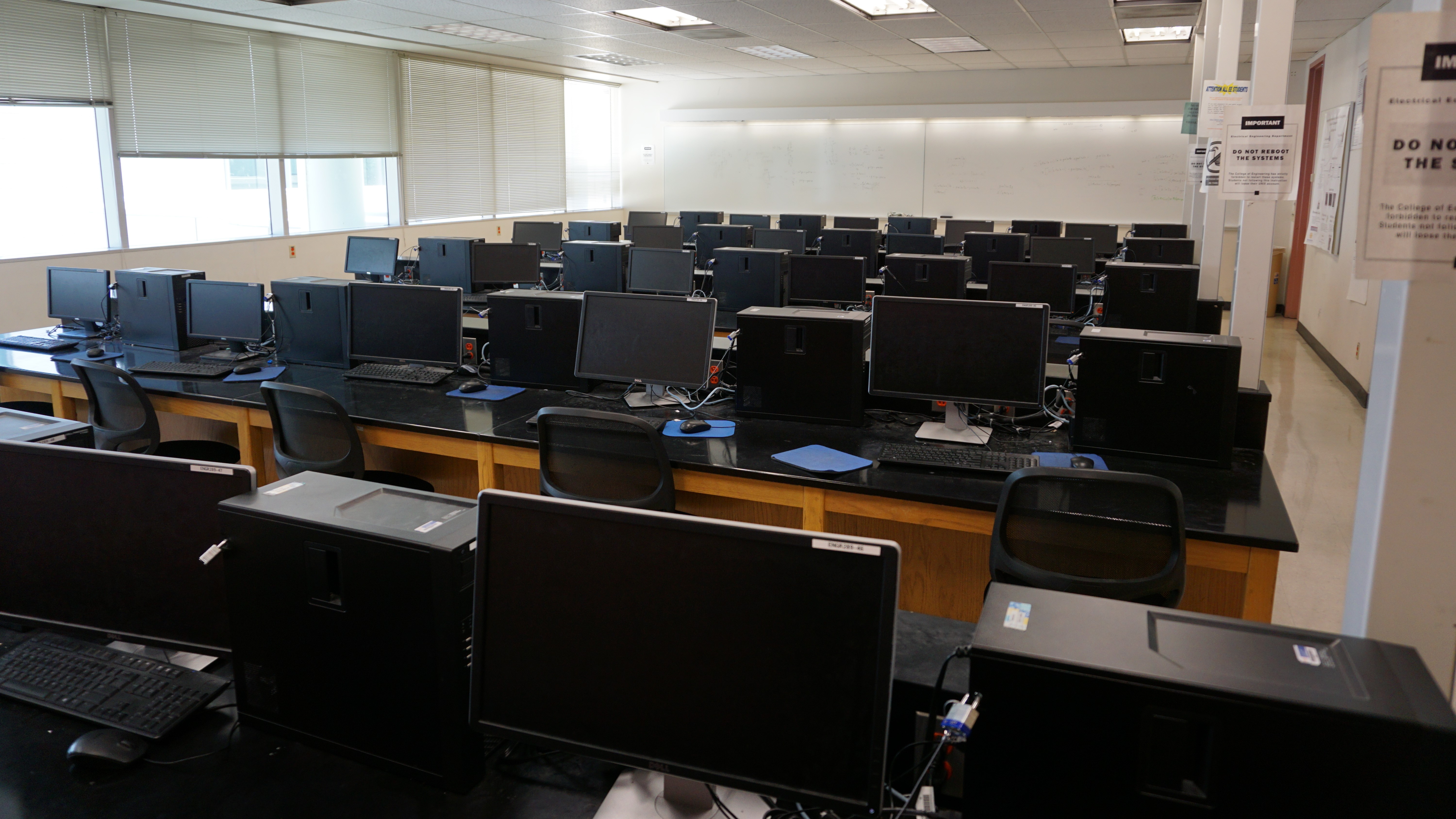 A classroom with multiple rows of computers and monitors.