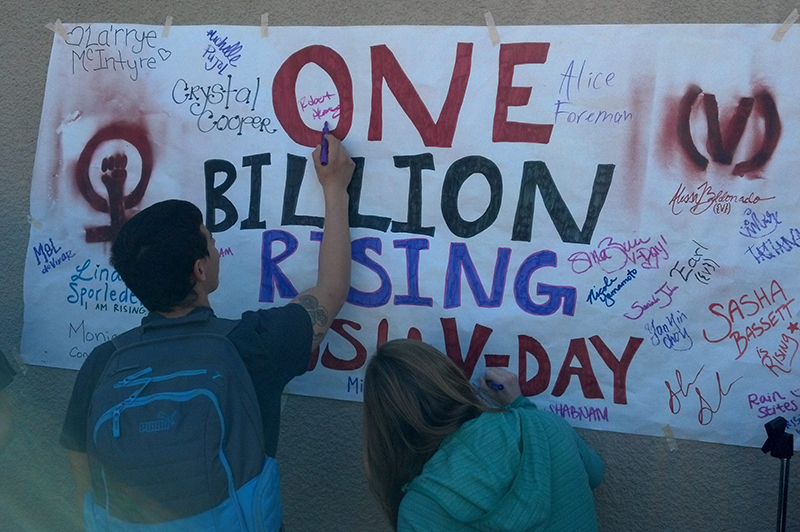 Two students writing on One Billion Rising Poster
