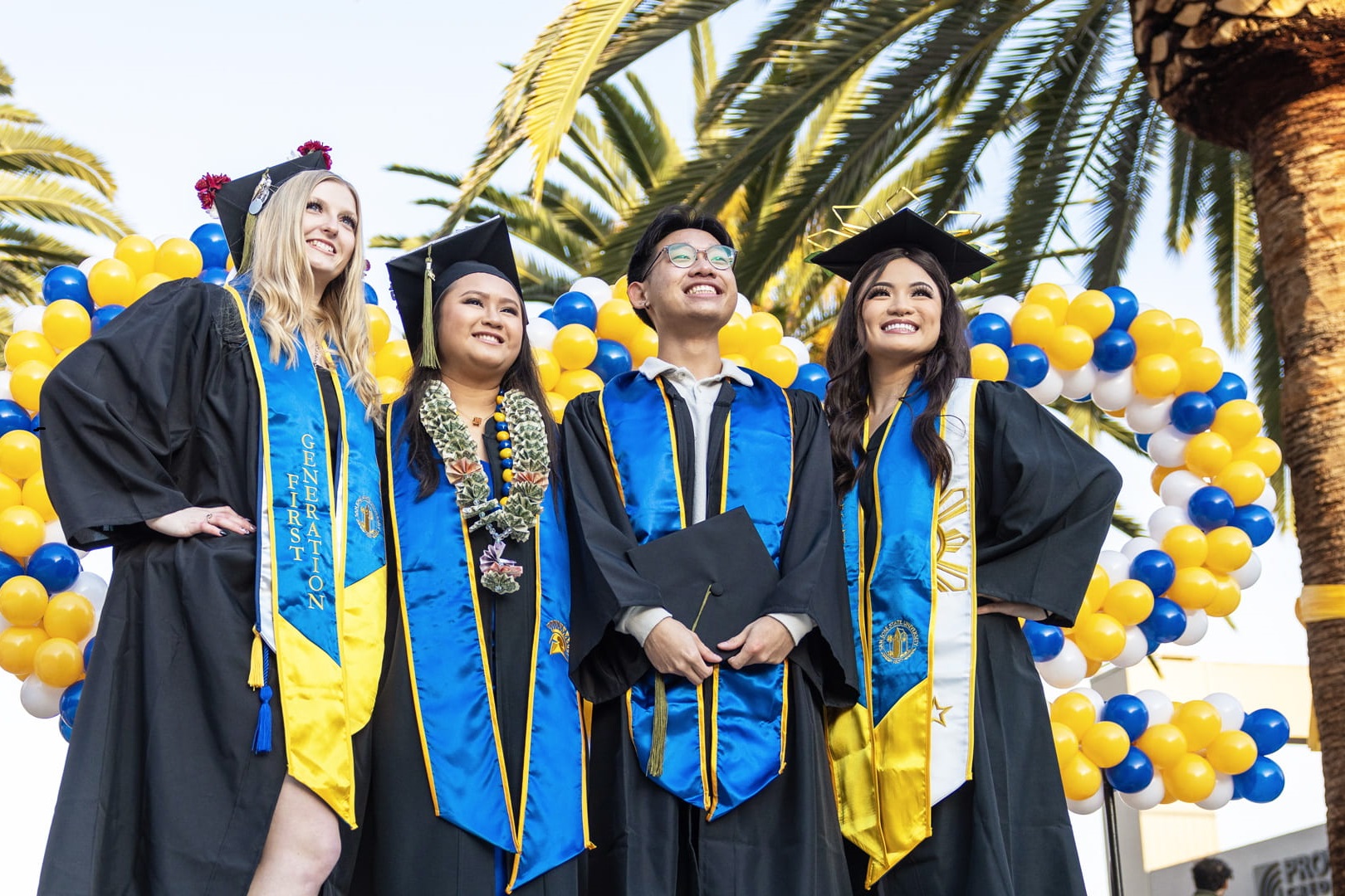 A group of San José State University graduates pose for a photo dressed in their graduation cap and gown. 