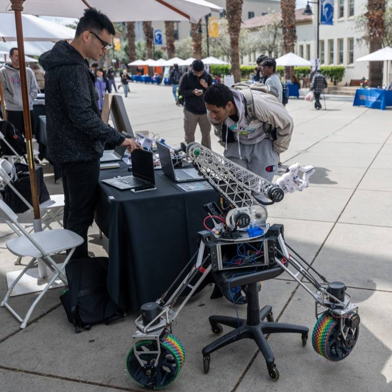 Engineering students displaying a wheeled robot
