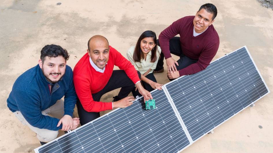 Professor with students in front of a solar panel.