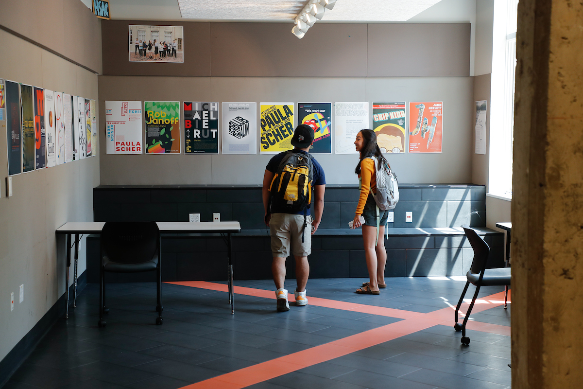 Students observing posters in a classroom