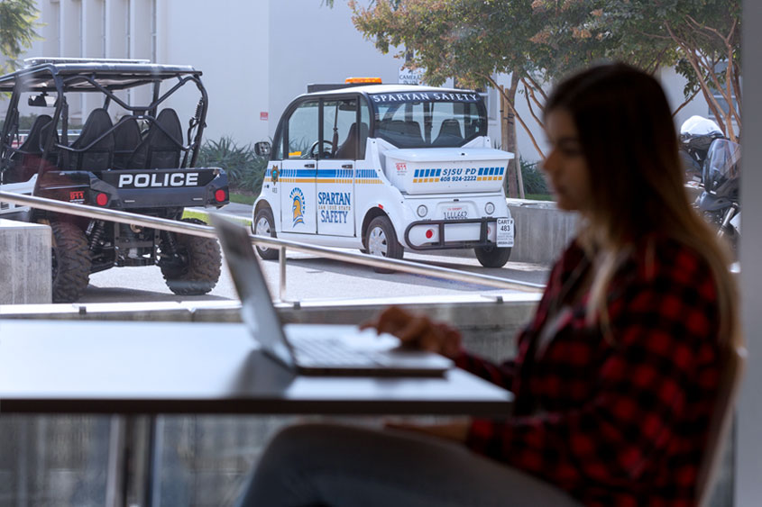 Student studying with police vehicles in the background.