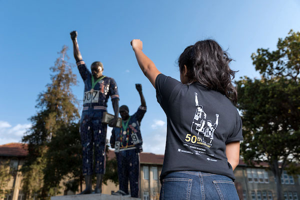 Student facing the statues of Tommie Smith and John Carlos.