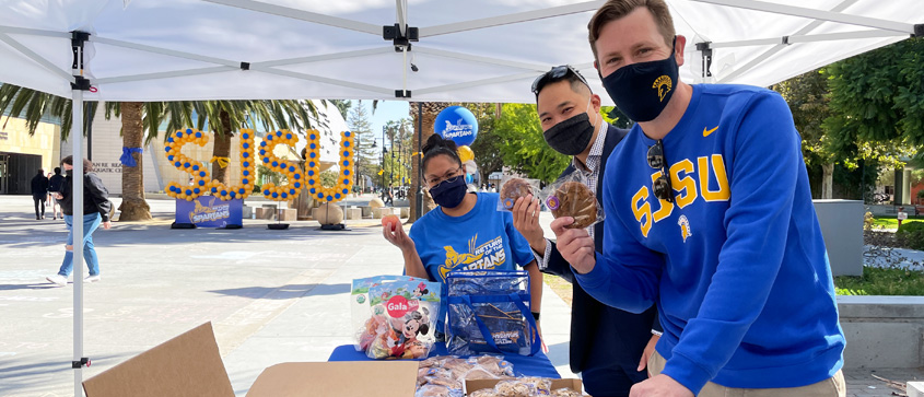 SJSU staff hold up cookies they are giving away on campus.