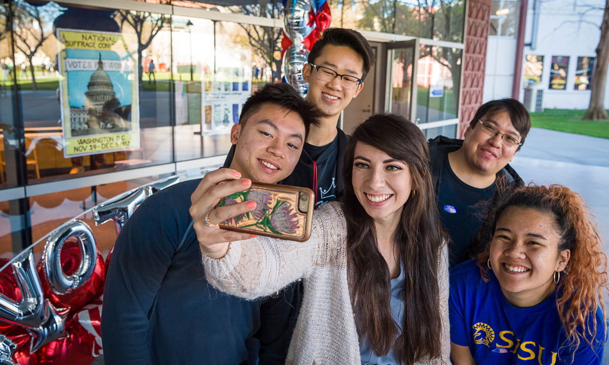SJSU students huddling together for a selfie at a voting center.