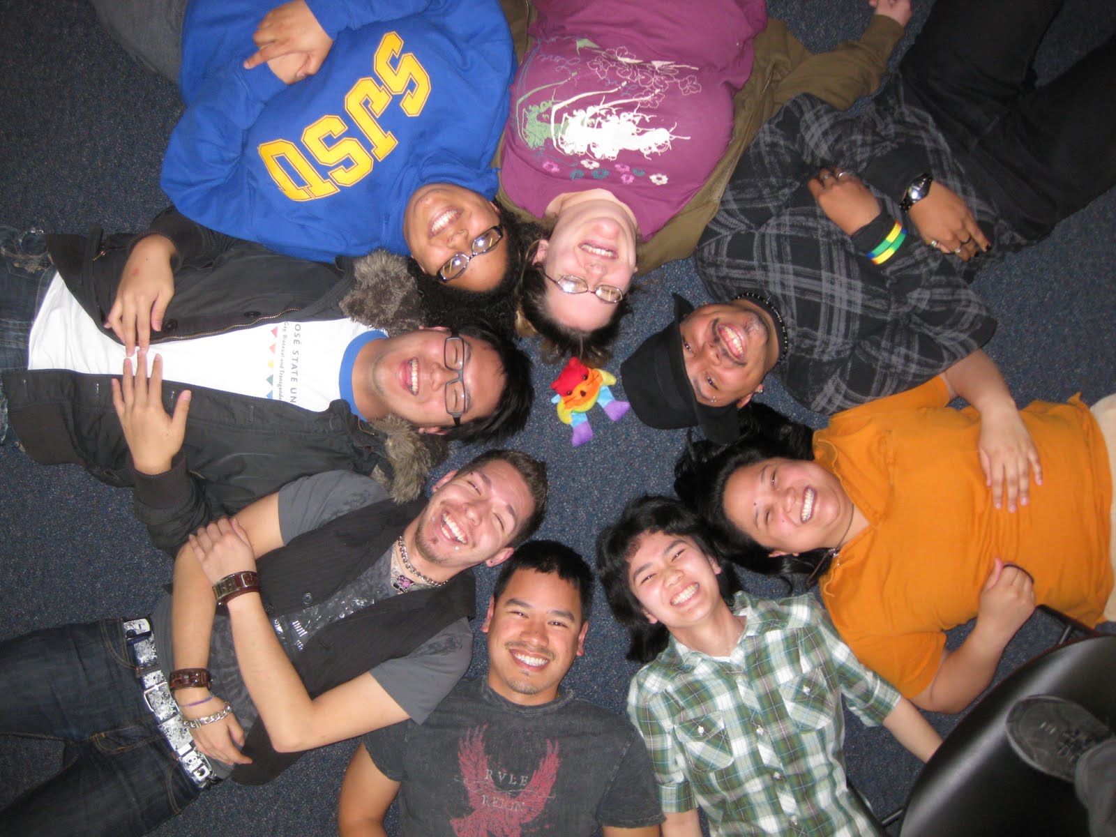 Group of students lying on floor with heads touching in circle.