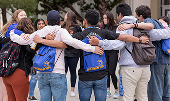 group of students standing outside in a big group hug