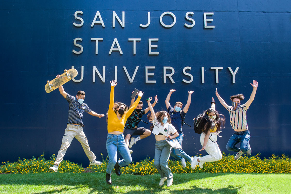 Students jumping in front of a wall that says San Jose State University.