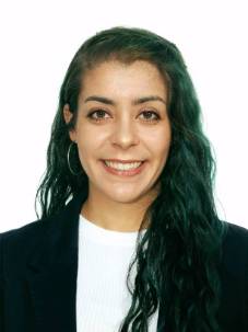 Headshot of Andrea, she has has long, green and  wavy hair, and she is wearing a black blazer with a white top.
