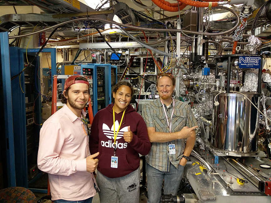 Tyanna, Daniel and Professor Wolcott pose in front of the TES detector