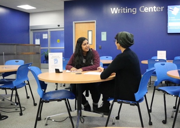 Picture of a writing center tutor and tutee having an in-person session at the library location.